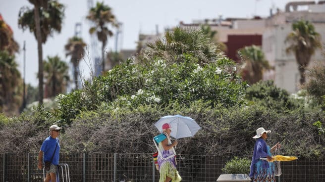 Bañistas se dirigen a la Playa de la Malvarrosa, a 12 de agosto de 2022