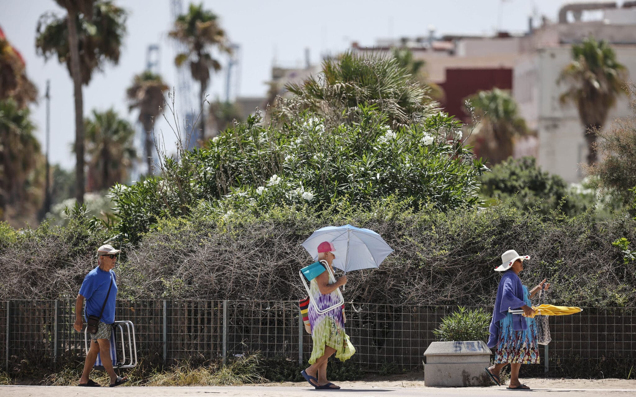 Bañistas se dirigen a la Playa de la Malvarrosa, a 12 de agosto de 2022