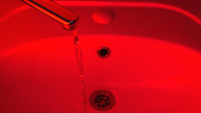 Una luz roja ilumina el lavabo de un baño. Una luz roja ilumina el lavabo de un baño.
