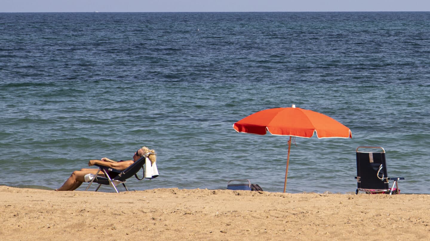 Una mujer toma el sol en la playa de las Marinas en Dénia.