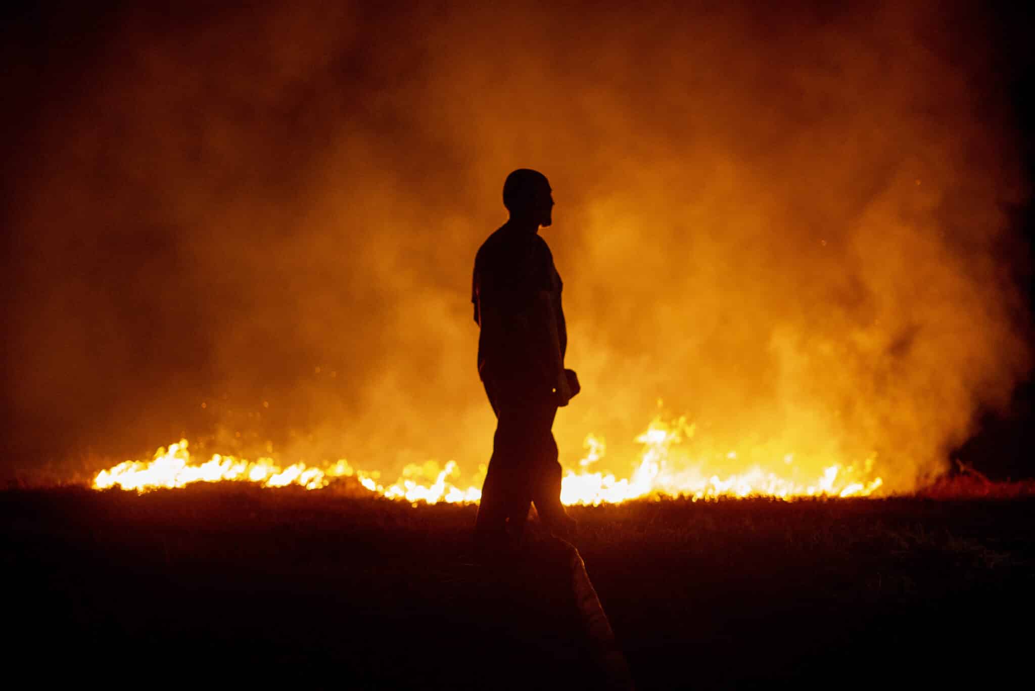 Un vecino ante las llamas mientras colabora en las labores de extinción del incendio de Cures, en Boiro, A Coruña