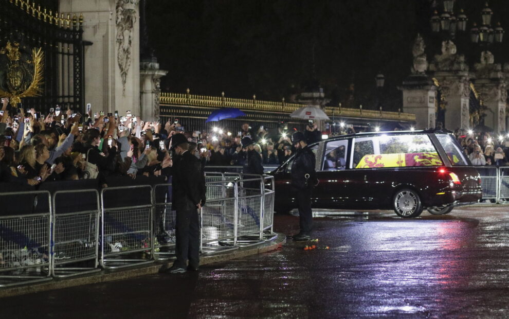Agentes de policía inclinan la cabeza mientras el coche fúnebre que transporta el ataúd de la reina Isabel II de Gran Bretaña se dirige hacia las puertas del Palacio de Buckingham en Londres