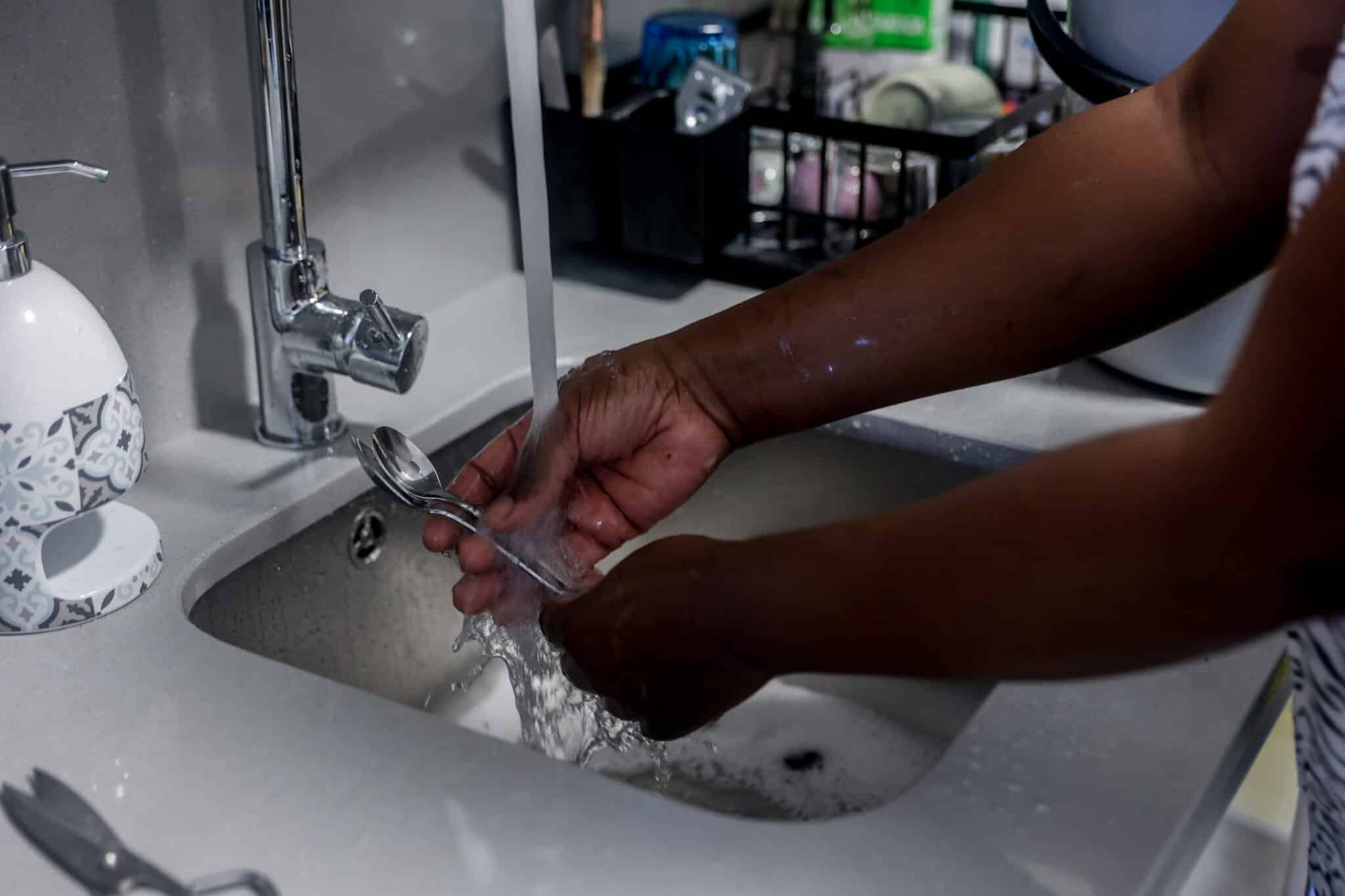 Una empleada de hogar friega cubiertos de cocina en una casa de Madrid.