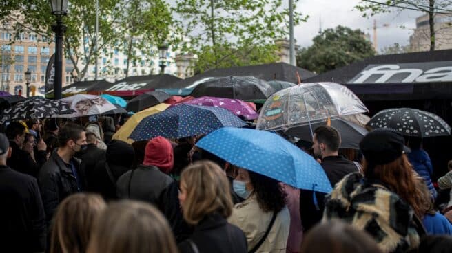 Varias personas, con paraguas, en la feria literaria de Sant Jordi, en el día Internacional del Libro, a 23 de abril de 2022, en Barcelona, (España)