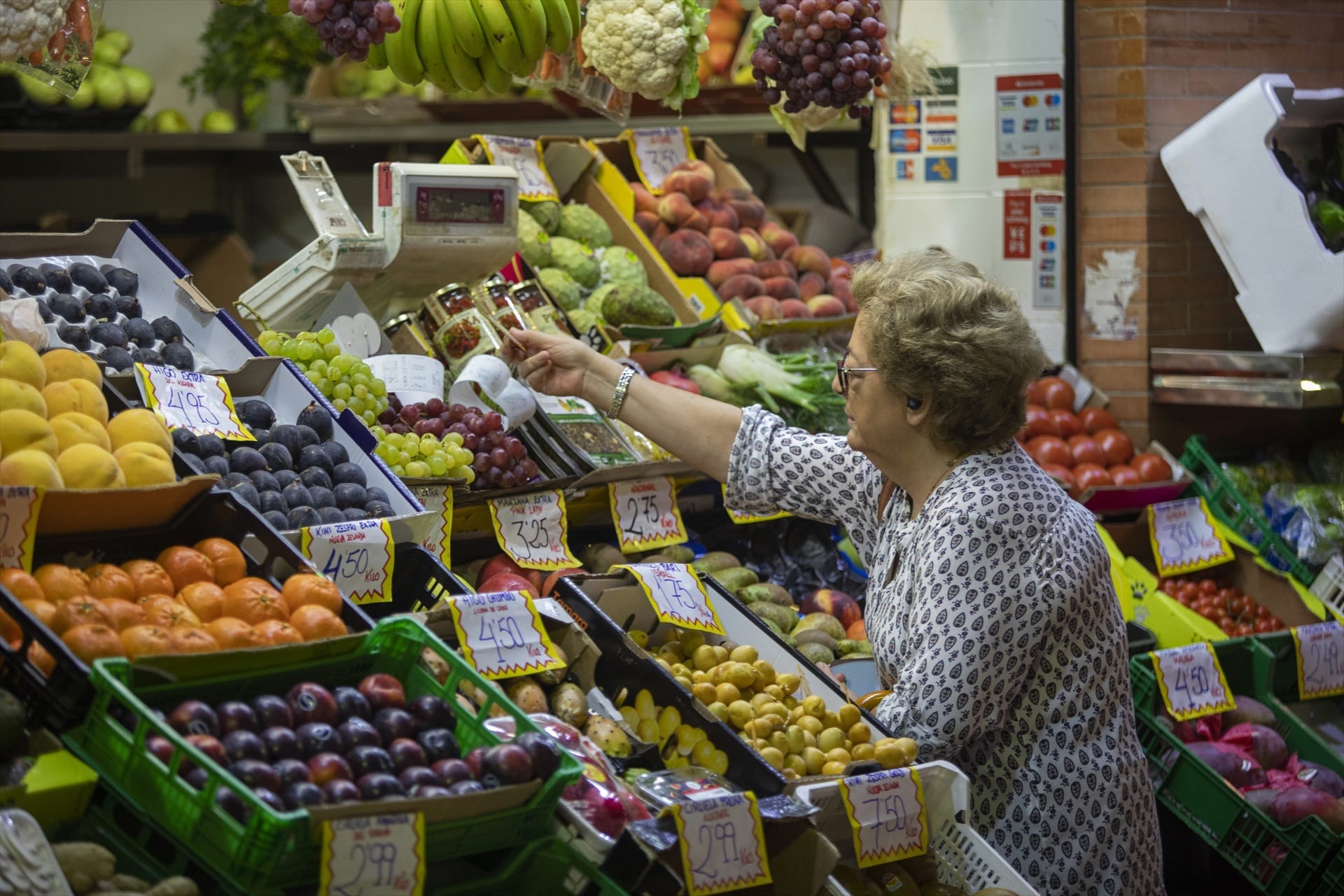 Una mujer compra en uno de los puestos del mercado de abastos de Triana.