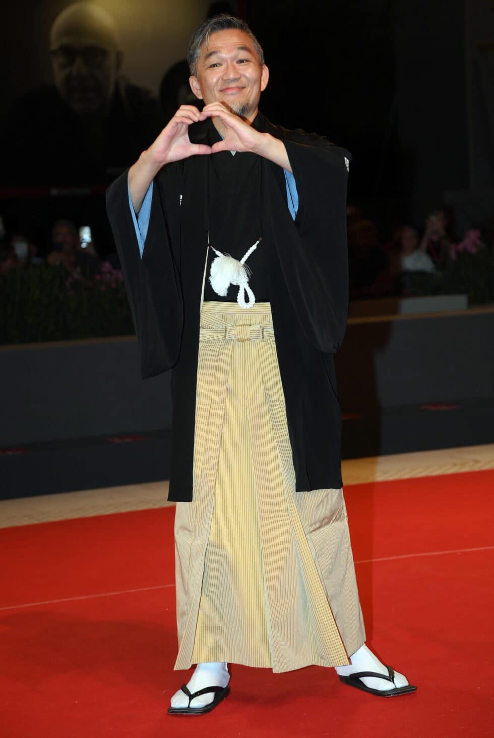 Atom Sunada, actor japonés en la película Love Life, con un kimono y haciendo un corazón con las manos en la alfombra roja del Festival de Venecia 2022