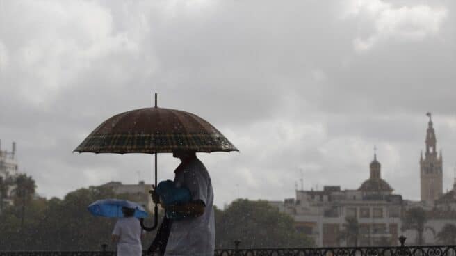 dos personas caminan bajo la lluvia por Sevilla este mes de septiembre