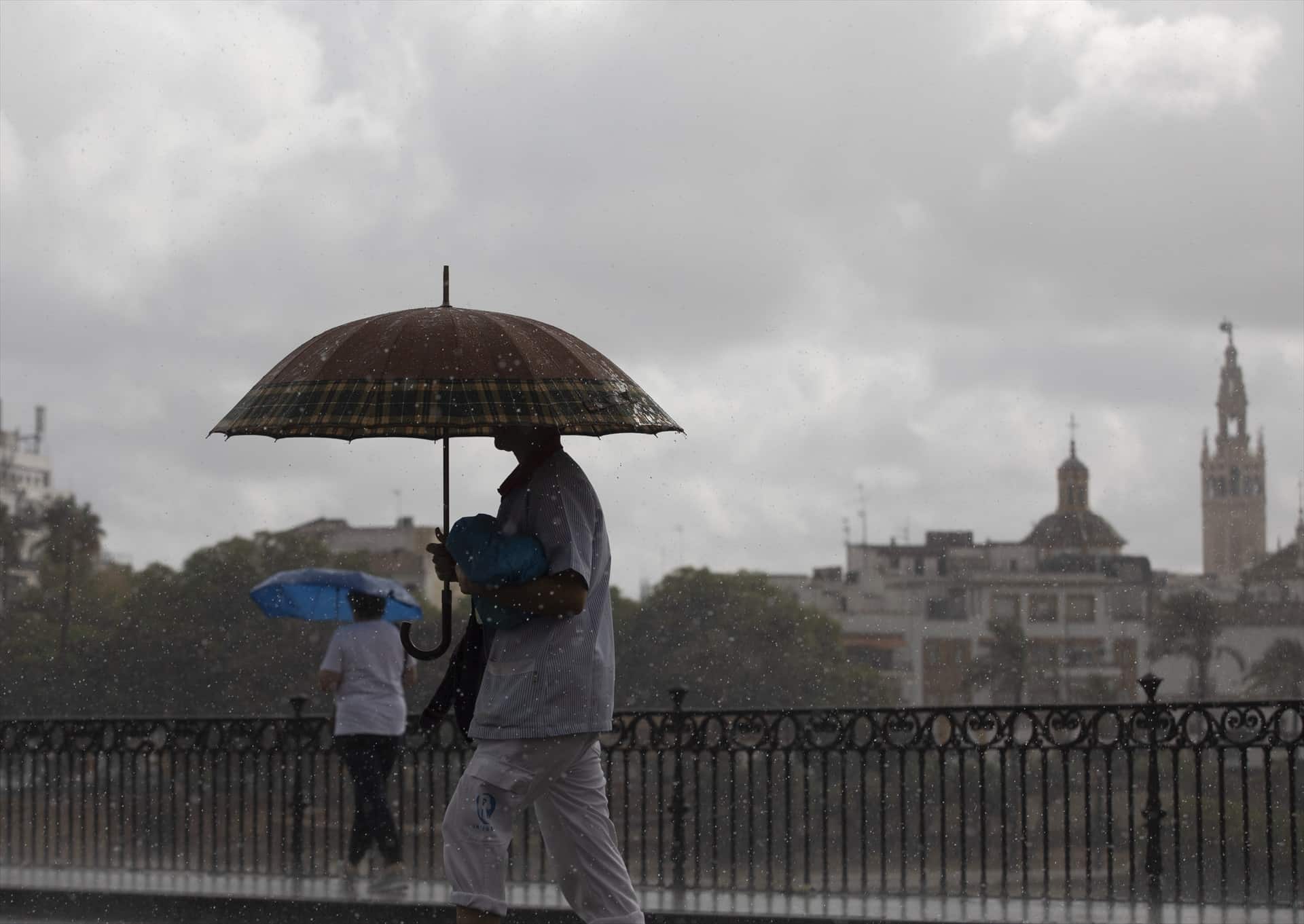 dos personas caminan bajo la lluvia por Sevilla este mes de septiembre