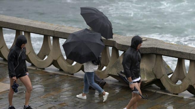 Gente caminando bajo la lluvia y el viento en el paseo marítimo de A Coruña