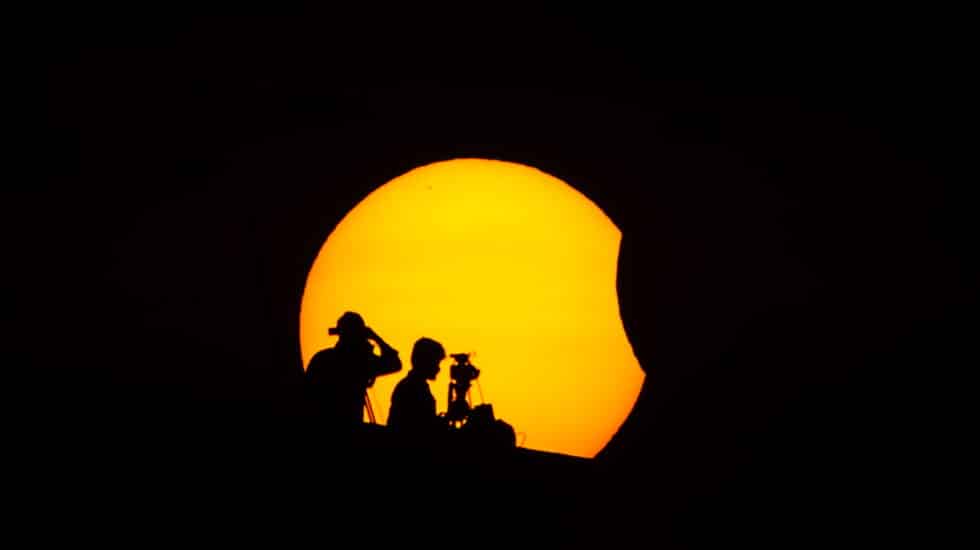 Profesionales ven el eclipse parcial solar en Chennai (India).