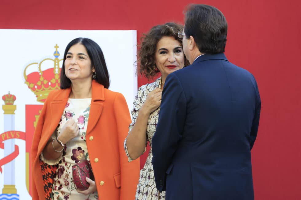 El presidente de Extremadura, Guillermo Fernández Vara conversa con la ministra de Hacienda, María Jesús Montero y la ministra de Sanidad, Carolina Darias en el palco de autoridades al desfile del Día de la Fiesta Nacional, este miércoles, en Madrid.