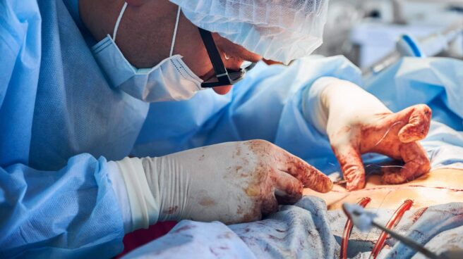 Male doctor placing sutures following an abdominoplasty procedure. Un doctor practica una cirugía estética abdominal.