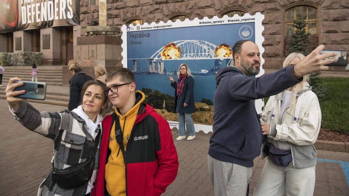 Ciudadanos se hacen fotos frente a un sello que simula las explosiones del puente de Crimea, en Kiev.