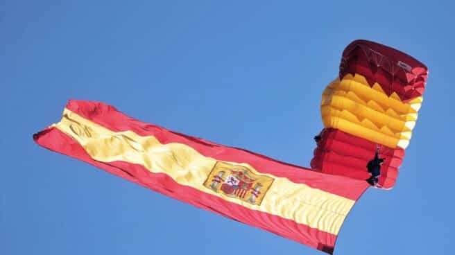 Un paracaidista despliega la bandera de España en el aire durante acto solemne de homenaje a la bandera nacional y desfile militar en el Día de la Hispanidad, a 12 de octubre de 2021, en Madrid, (España)