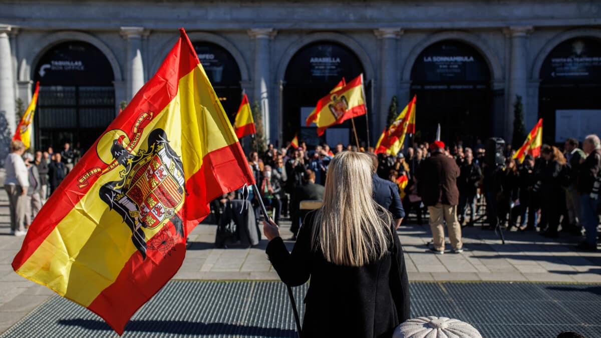 Varias personas, con banderas de España con el águila de San Juan, asisten a un acto organizado por el Movimiento Católico español (MCE) en memoria de Francisco Franco y José Antonio Primo de Rivera, en la Plaza de Oriente, el domingo
