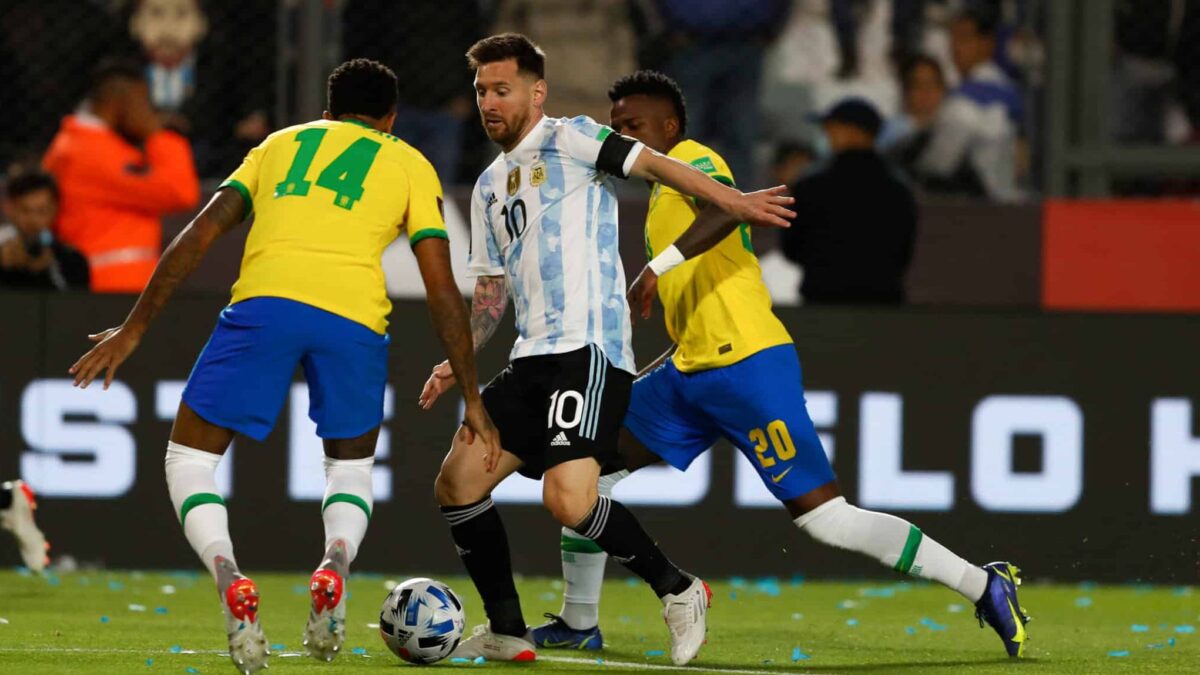 Eder Militao, Lionel Messi y Vini Jr disputan por un balón durante la clasificación al Mundial Qatar 2022