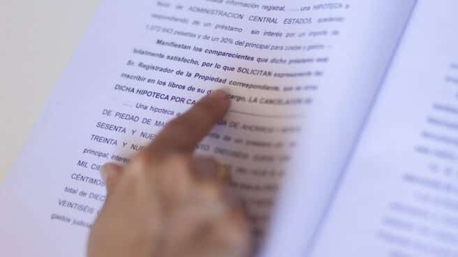 Firma de compraventa de una hipoteca, que se ha pedido revisar la clausula de abuso Una mujer señala una escritura de compraventa de una hipoteca