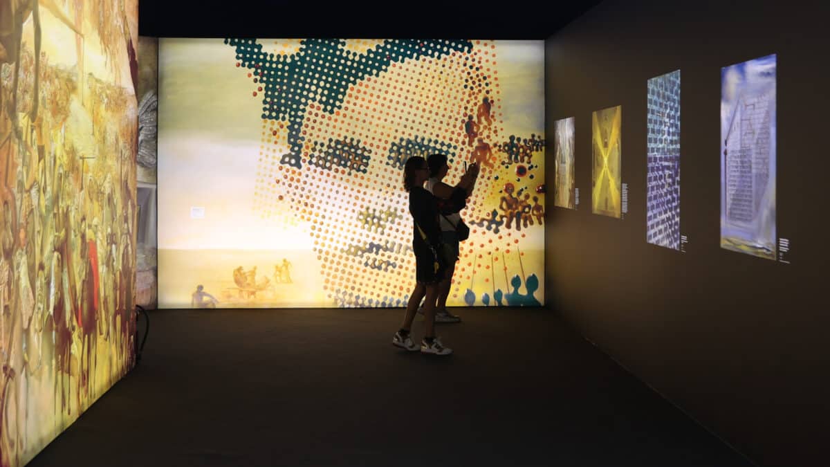 Dos mujeres fotografían obras digitalizadas de Dalí durante la visita a la exposición ‘Desafío Dalí’, en IFEMA