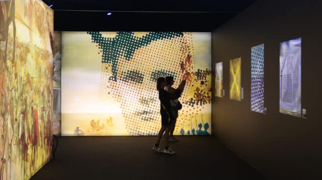 Dos mujeres fotografían obras digitalizadas de Dalí durante la visita a la exposición ‘Desafío Dalí’, en IFEMA