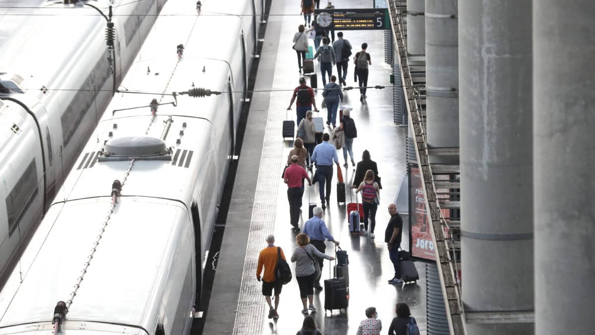 Varios pasajeros con maletas en el andén de un tren en la estación de Puerta de Atocha