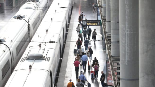 Varios pasajeros con maletas en el andén de un tren en la estación de Puerta de Atocha