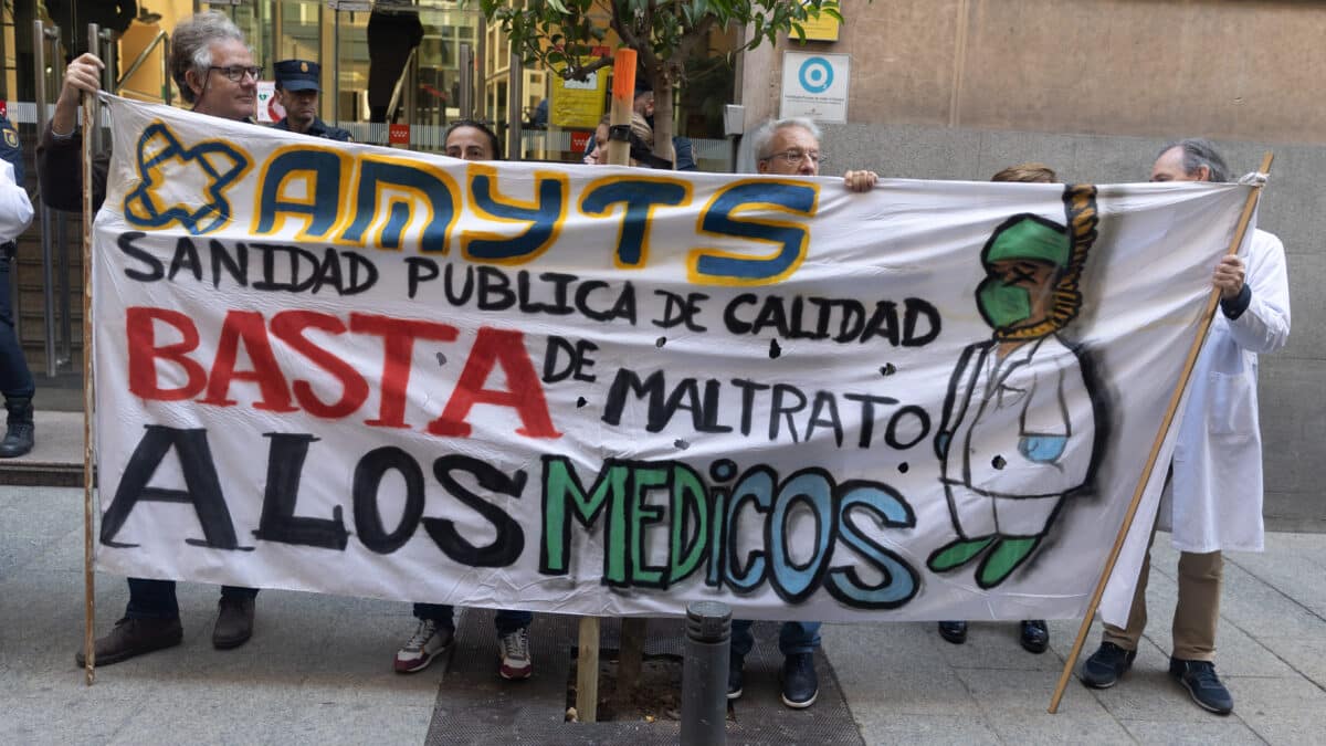 Varias personas con una pancarta en la que se lee: 'Sanidad pública de calidad, basta de maltrato a los médicos' durante una concentración enmarcada en el inicio del modelo de atención urgente extrahospitalaria