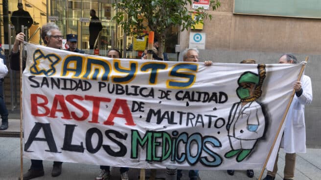 Varias personas con una pancarta en la que se lee: 'Sanidad pública de calidad, basta de maltrato a los médicos' durante una concentración enmarcada en el inicio del modelo de atención urgente extrahospitalaria