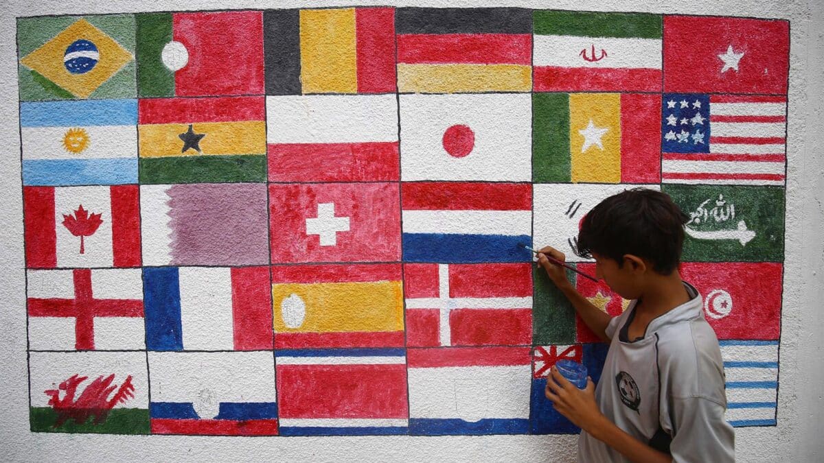 Un niño pinta en Karachi (Pakistán) las banderas de todos los países que participan en el Mundial de fútbol Qatar 2022.