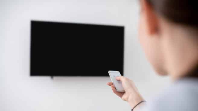 Female turning on the wall-mounted plasma TV