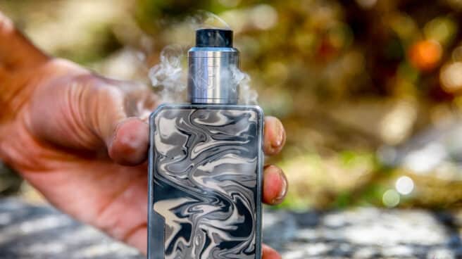 Un hombre sostiene un vapeador. Un hombre sostiene un vapeador.