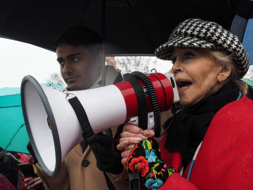 La actriz estadounidense Jane Fonda (derecha) grita consignas en un megáfono durante una protesta para crear conciencia sobre el cambio climático frente al Capitolio de los EE. UU.