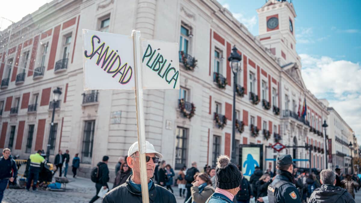 Un hombre con un cartel que reza 'SANIDAD PÚBLICA' durante una manifestación de médicos y pediatras en la sede del Gobierno regional