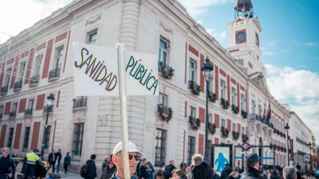 Un hombre con un cartel que reza 'SANIDAD PÚBLICA' durante una manifestación de médicos y pediatras en la sede del Gobierno regional