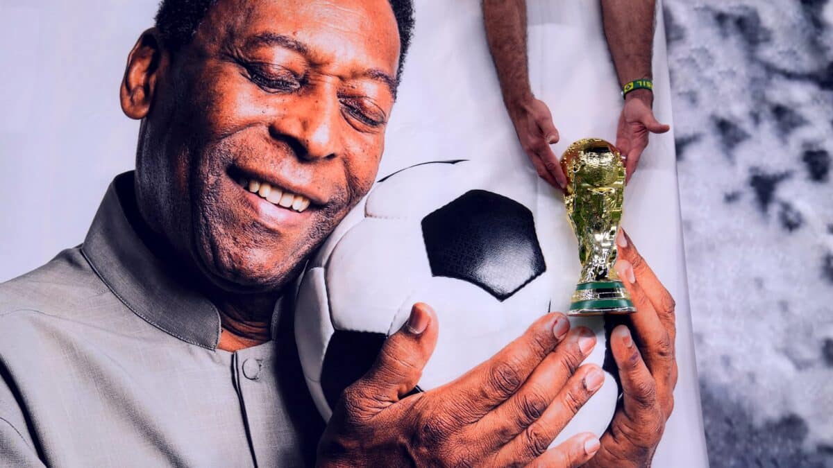 Un aficionado de Brasil sostiene una réplica del trofeo de la Copa del Mundo sobre una foto del ex jugador Pele