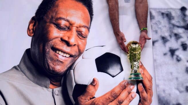 Un aficionado de Brasil sostiene una réplica del trofeo de la Copa del Mundo sobre una foto del ex jugador Pele