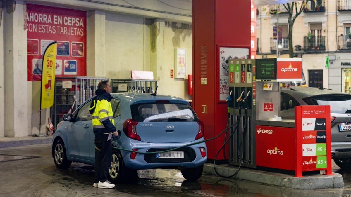 Una persona echa gasolina del surtidor de una gasolinera.