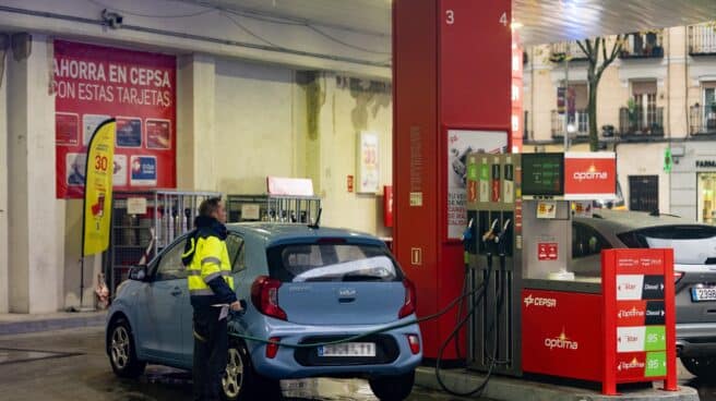 Una persona echa gasolina del surtidor de una gasolinera.