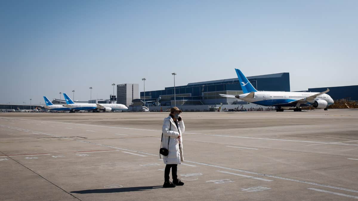 Una mujer con destino a Beijing usa su teléfono antes de abordar un avión en el Aeropuerto Internacional Xiamen Gaoqi en Xiamen, provincia de Fujian