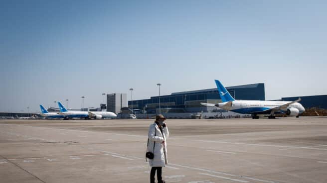 Una mujer con destino a Beijing usa su teléfono antes de abordar un avión en el Aeropuerto Internacional Xiamen Gaoqi en Xiamen, provincia de Fujian