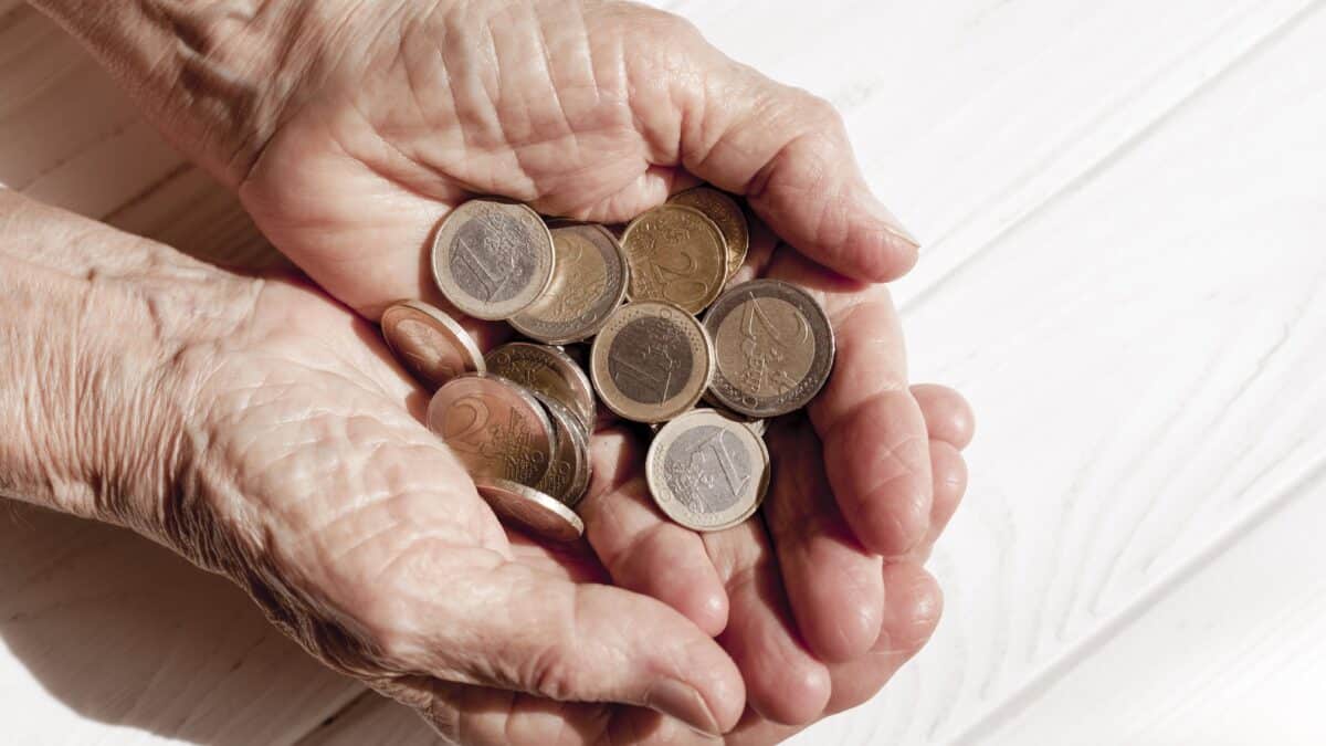 Una persona mayor sostiene monedas en sus manos.