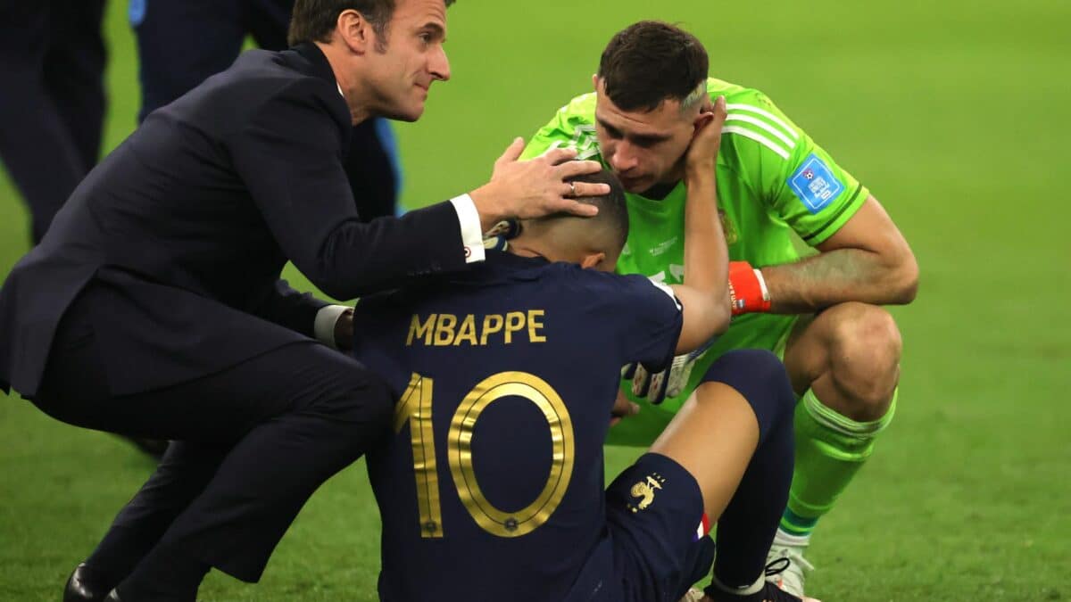 Kylian Mbappé recibe el consuelo del Dibu Martínez y Emmanuel Macron tras la final del Mundial de Qatar.