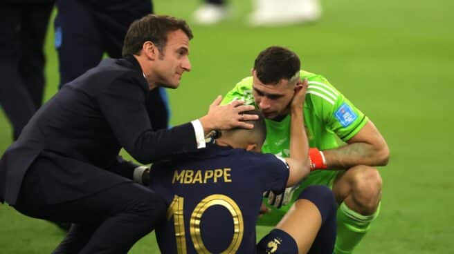 Kylian Mbappé recibe el consuelo del Dibu Martínez y Emmanuel Macron tras la final del Mundial de Qatar.