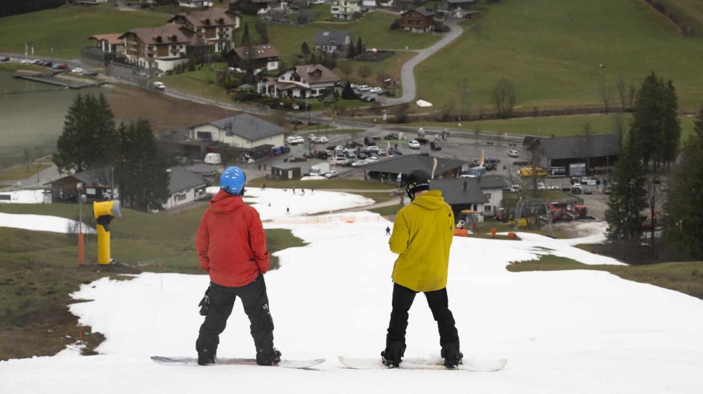 Esquiadores en los Alpes suizos se deslizan por pistas de esquí creadas con cañones de nieve ante la ausencia de nieve.