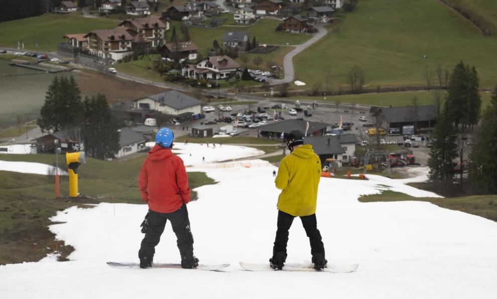 Esquiadores en los Alpes suizos se deslizan por pistas de esquí creadas con cañones de nieve ante la ausencia de nieve.