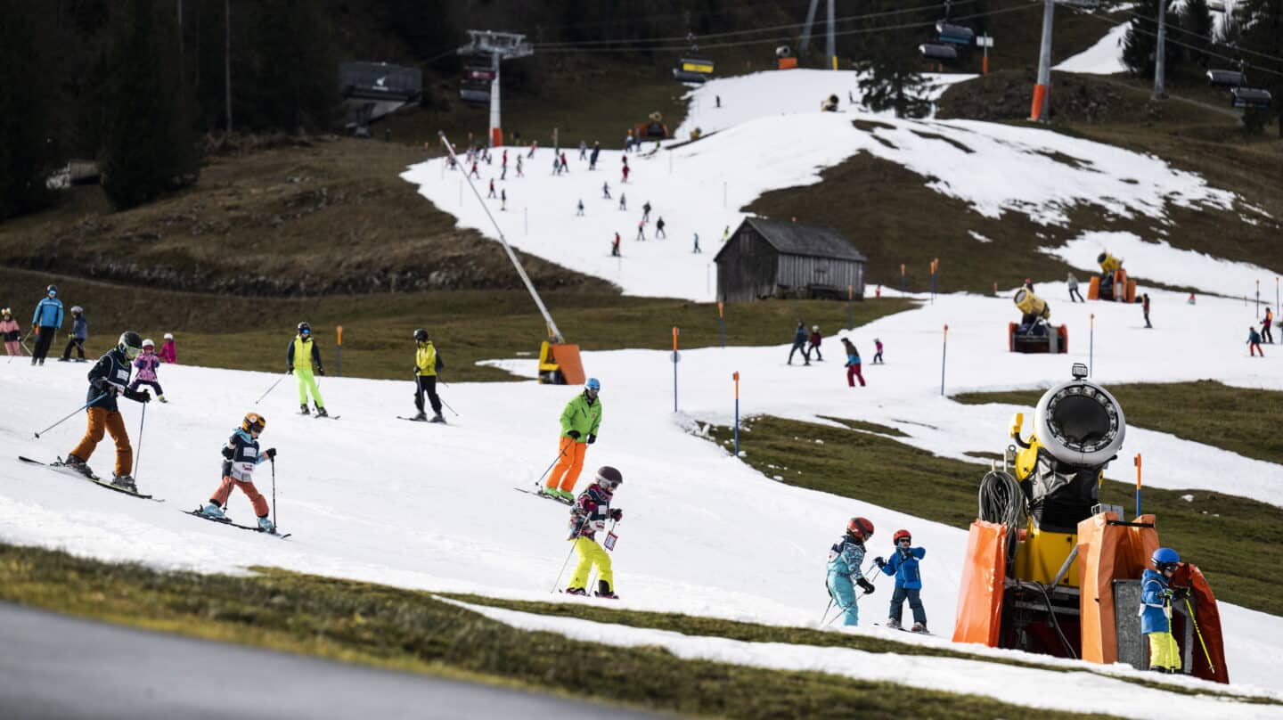 Esquiadores en los Alpes suizos se deslizan por pistas de esquí creadas con cañones ante la ausencia de nieve.