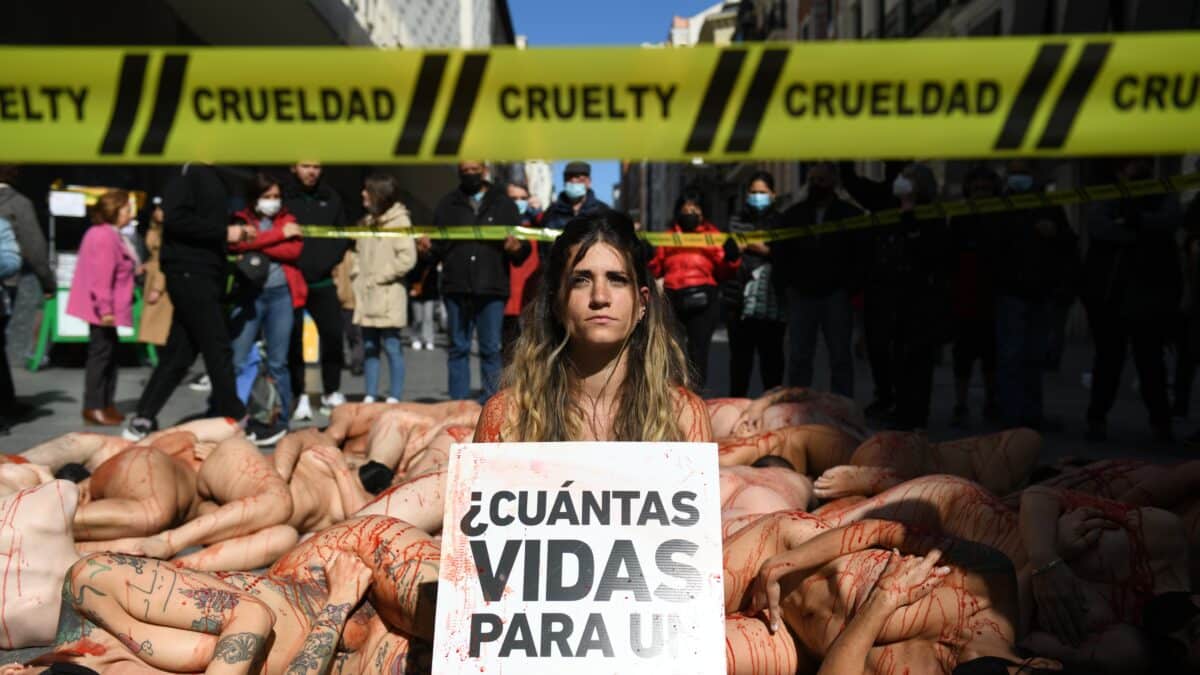 Varias chicas desnudas con pintura roja sobre el cuerpo, con una pancarta que reza '¿Cuántas vidas para un abrigo?' en una protesta contra la industria peletera