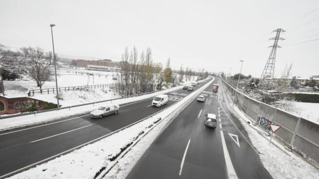 Varios coches circulan por una carretera con los laterales cubiertos de nieve