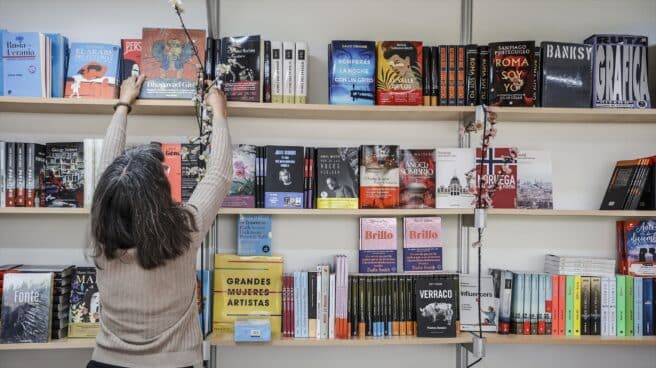 Una mujer coloca un libro en la estantería durante la inauguración de la Feria del Libro 2022 de Valencia.