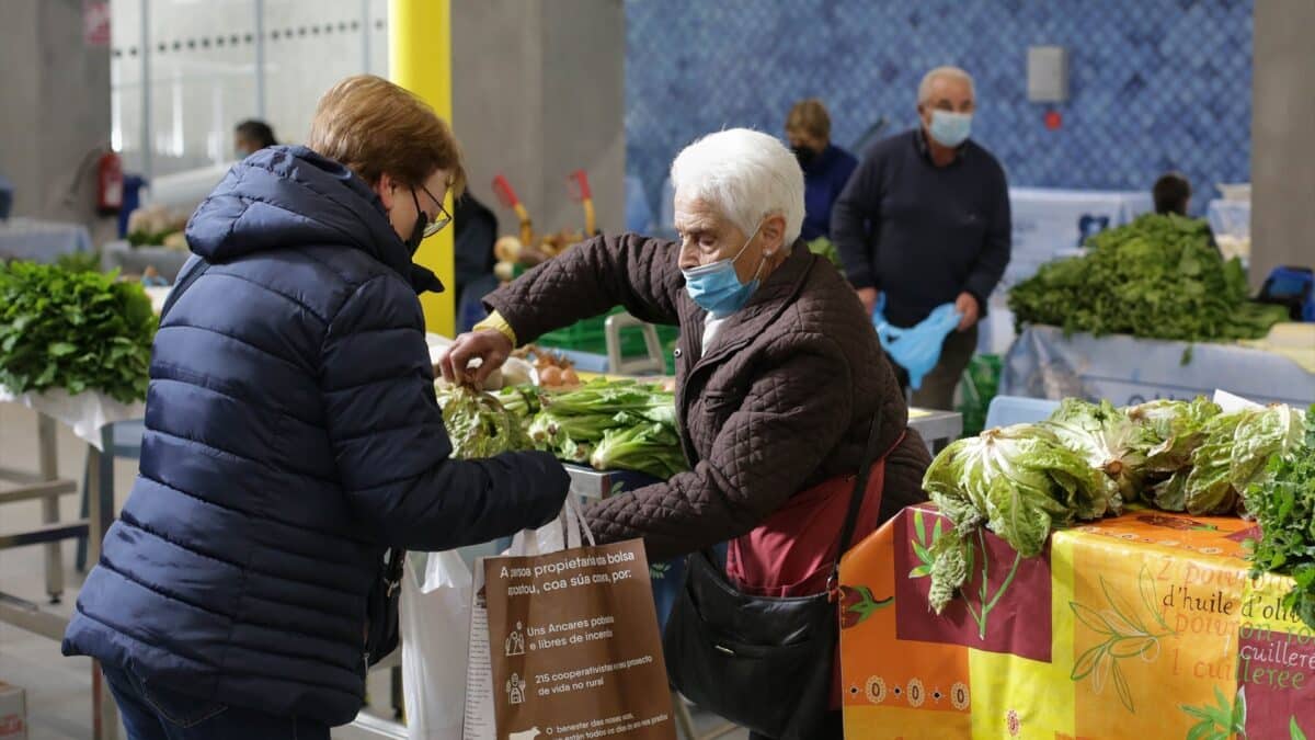 Una mujer compra verduras en un puesto del mercado tradicional de la Plaza de Abastos de Lugo.