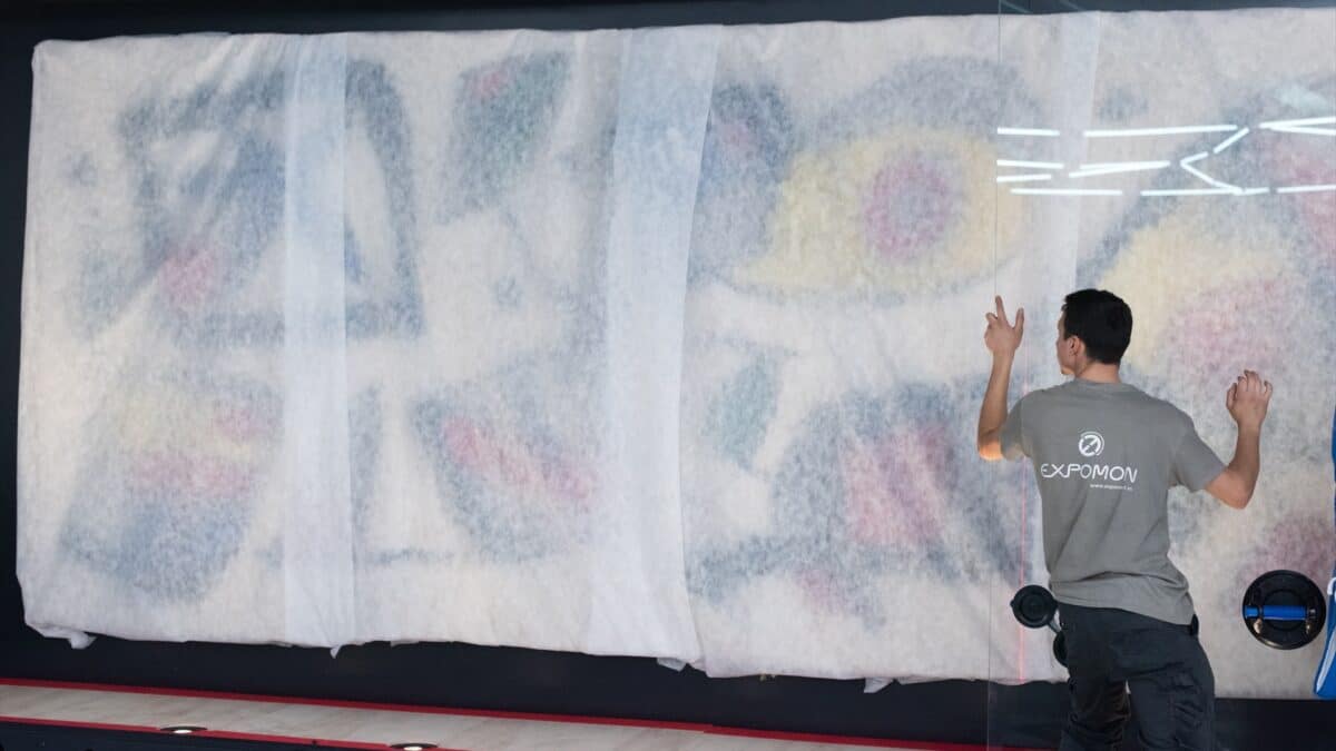 Un trabajador participa en la colocación del tapiz de Joan Miró y Josep Royo, en CaixaForum Madrid.